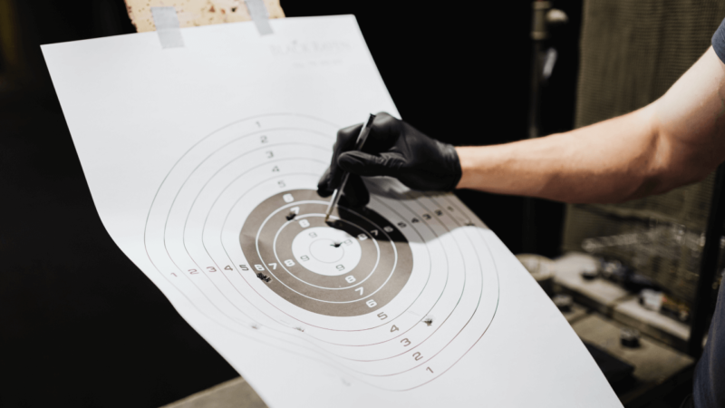 A piece of paper with a target and bullet holes in the paper. 