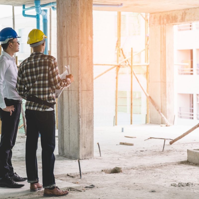 Asian contractor and engineer inspecting material in construction building.