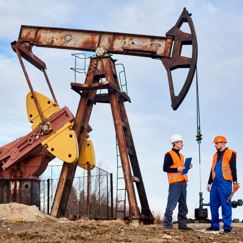 Two,Petroleum,Engineers,In,Helmets,And,Work,Vests,Standing,On